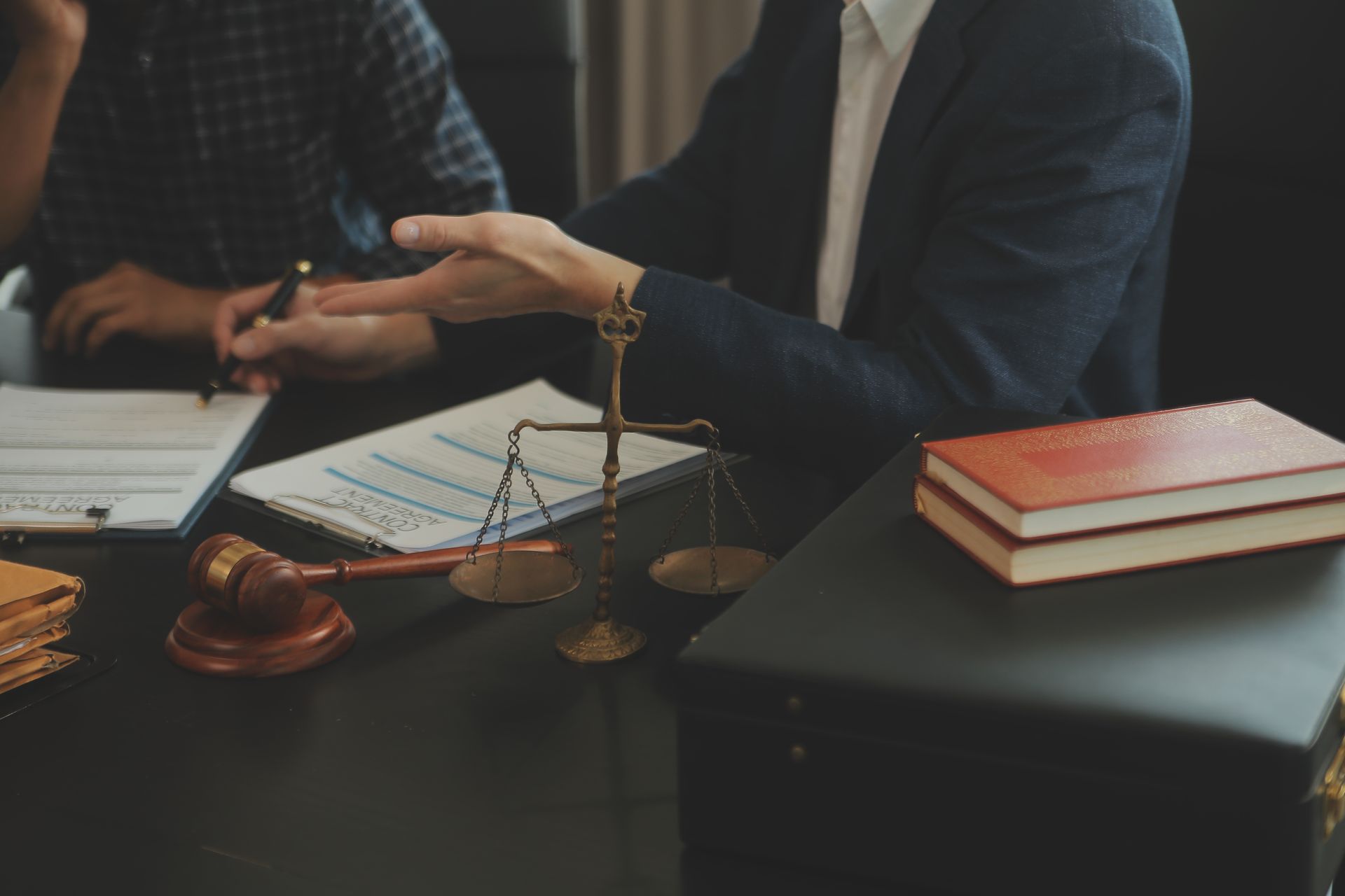 A man is sitting at a table with a scale of justice and a gavel.