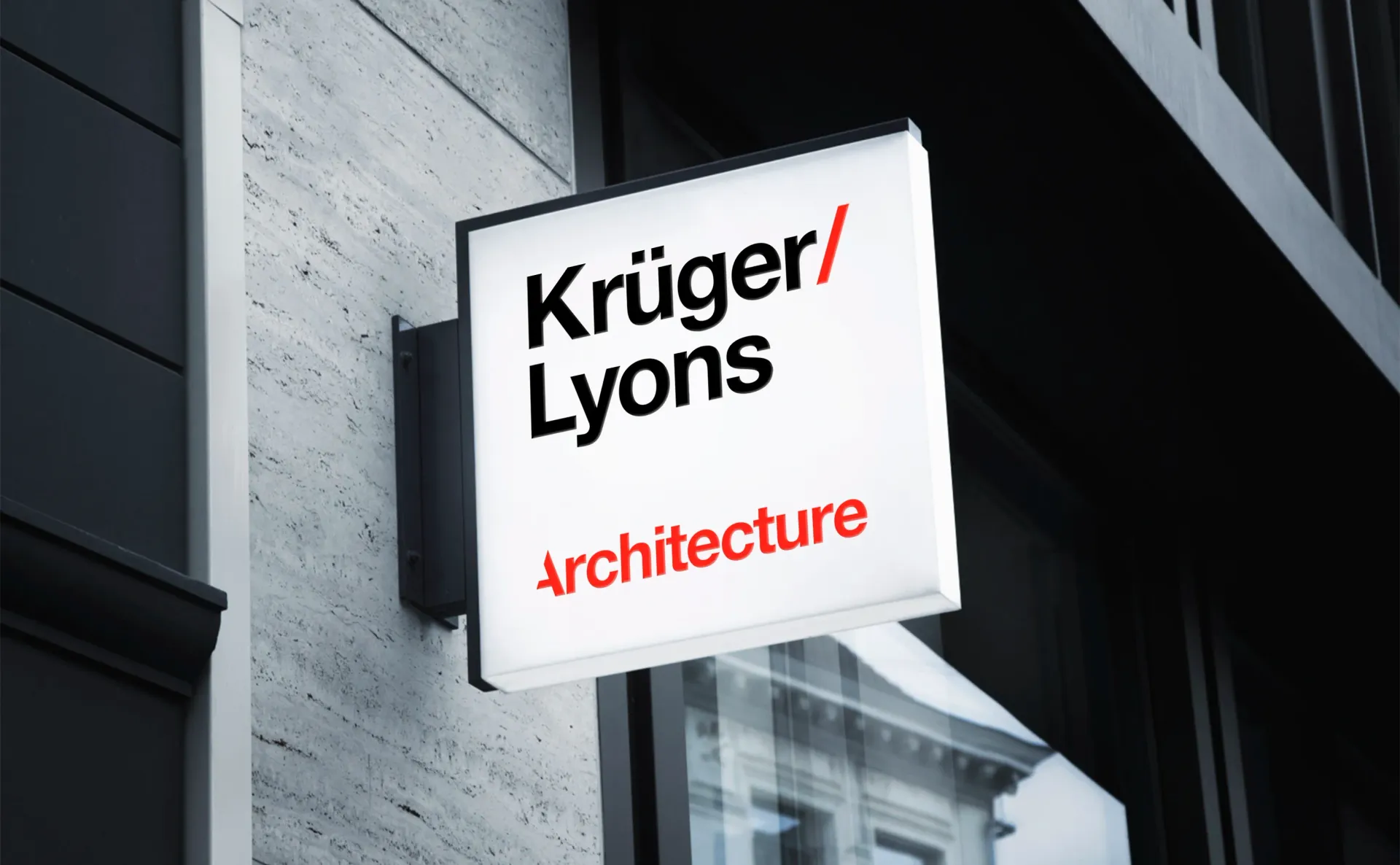 Sign for Kruger/Lyons Architecture on a building exterior, with red and black text on a white square.