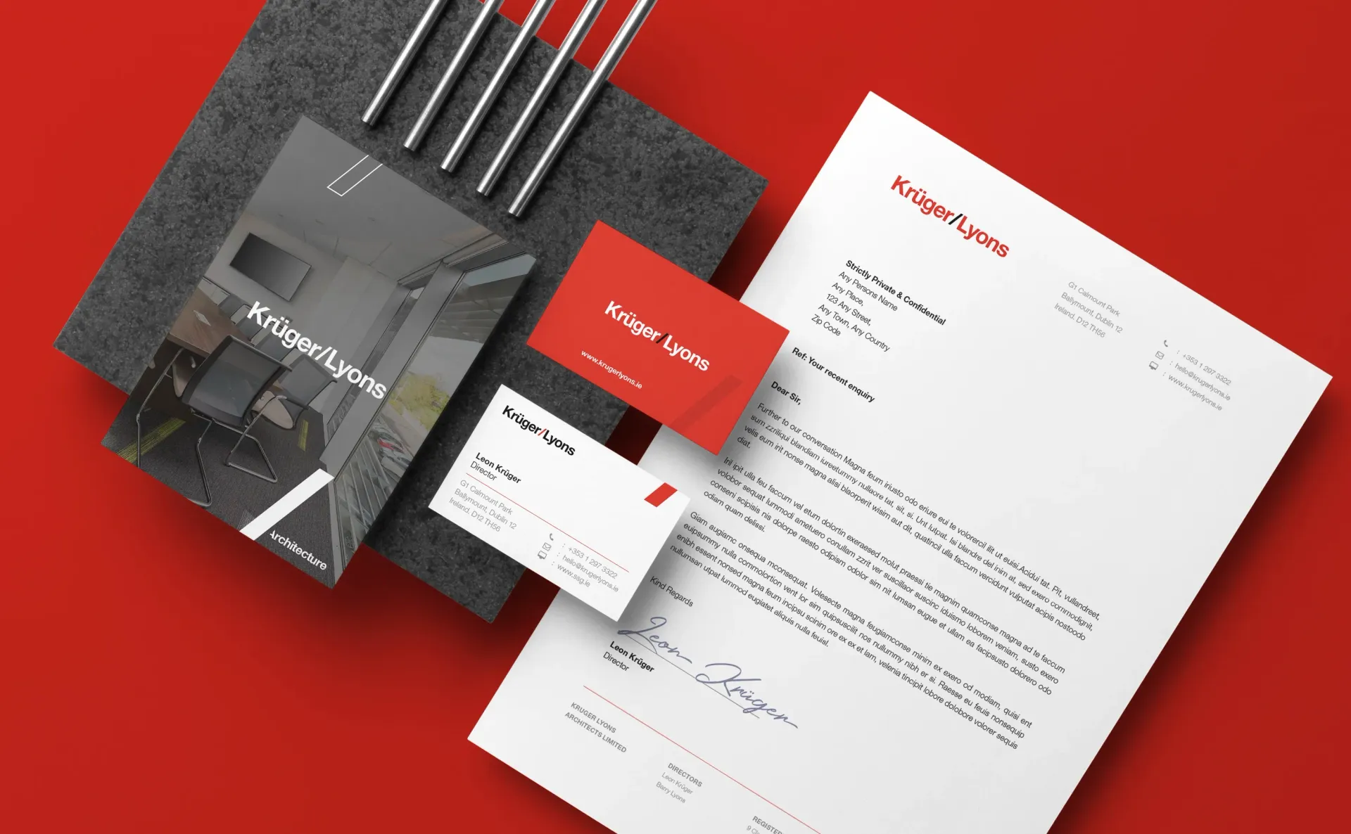 Stationery mockup with red and gray elements: business cards, letterhead, and notebook on a red surface.