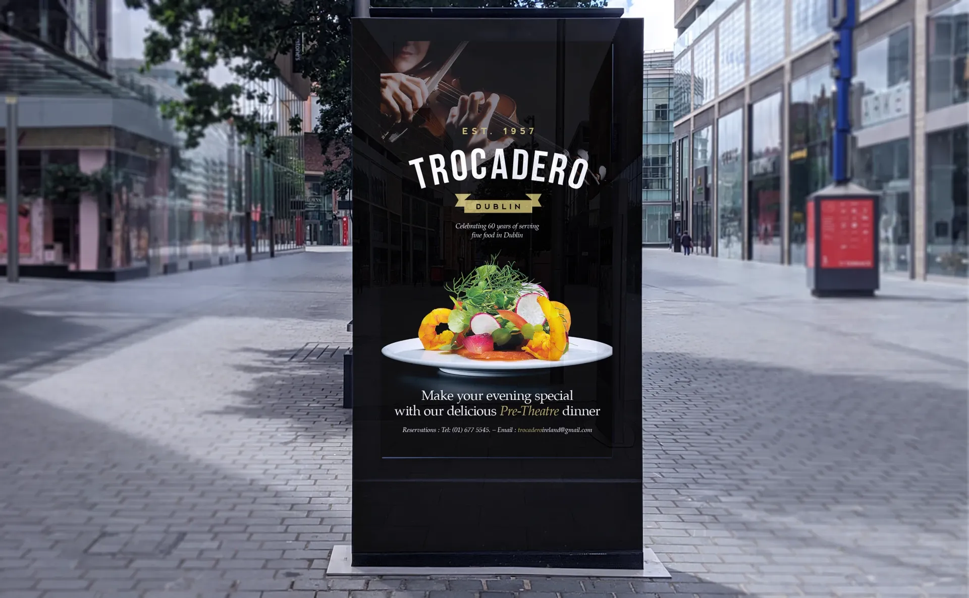 Black advertising kiosk on a city street, displaying a food advertisement for 