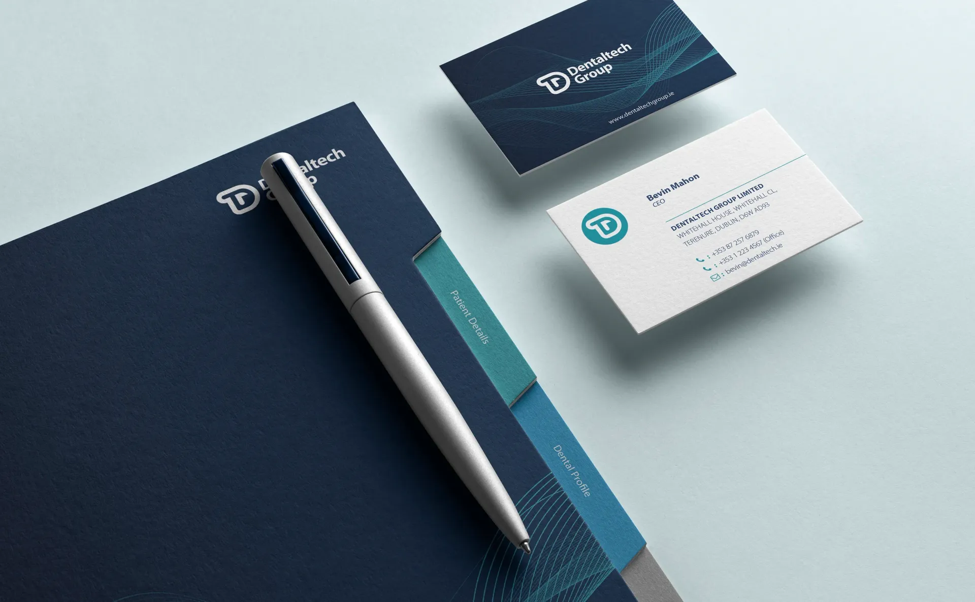 Branded office stationery: folder, pen, and business cards in navy and teal, on a light blue surface.
