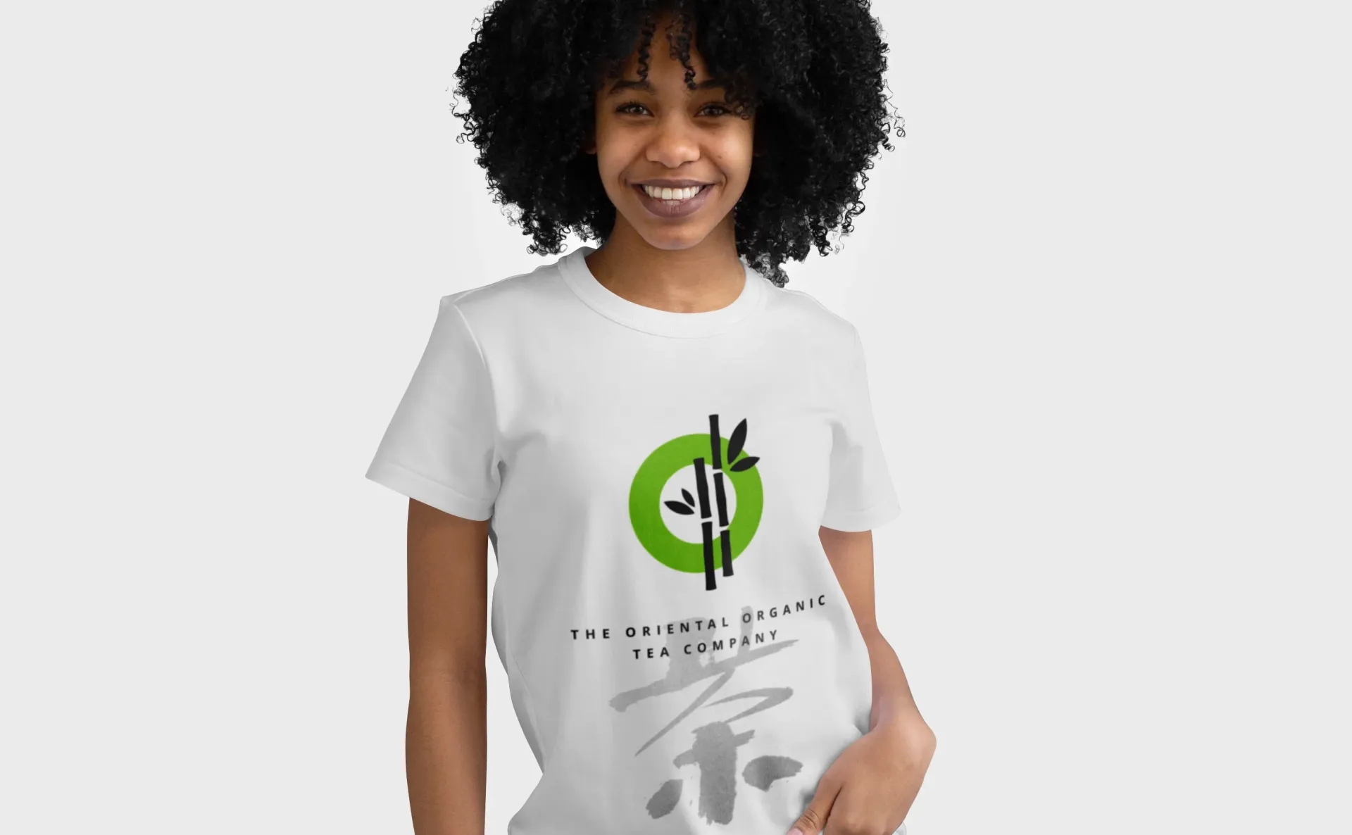 Woman in white t-shirt smiles, shirt has green circle, bamboo graphic and text.