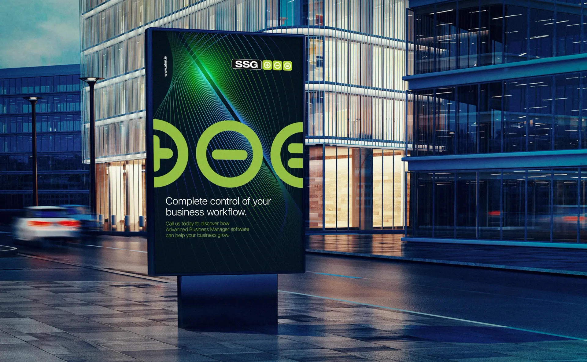 Billboard in front of modern buildings; green and yellow graphic with text. Street scene at dusk.