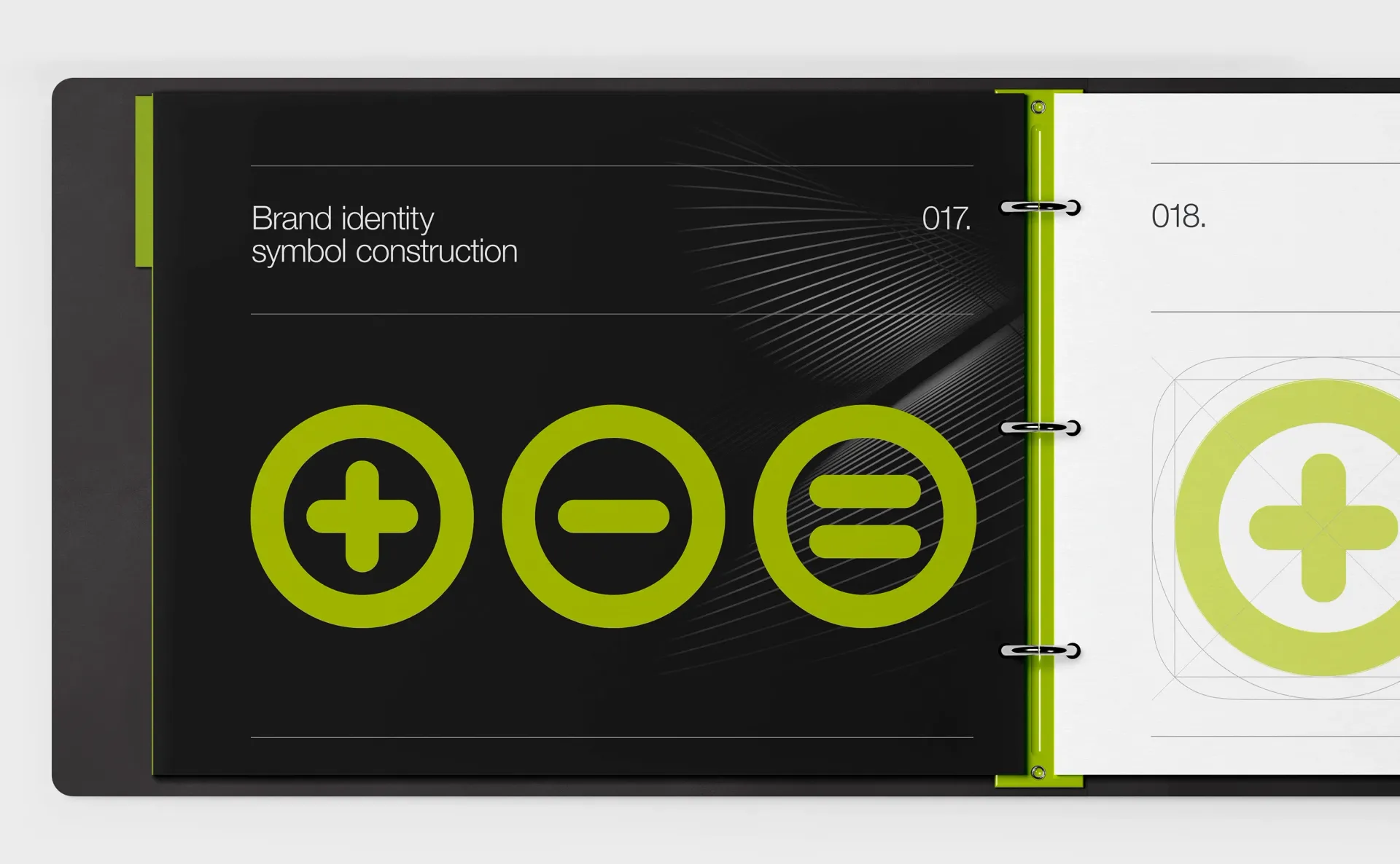 Black and white open binder with math symbols: plus, minus, equals in green on dark background and plus sign on white.