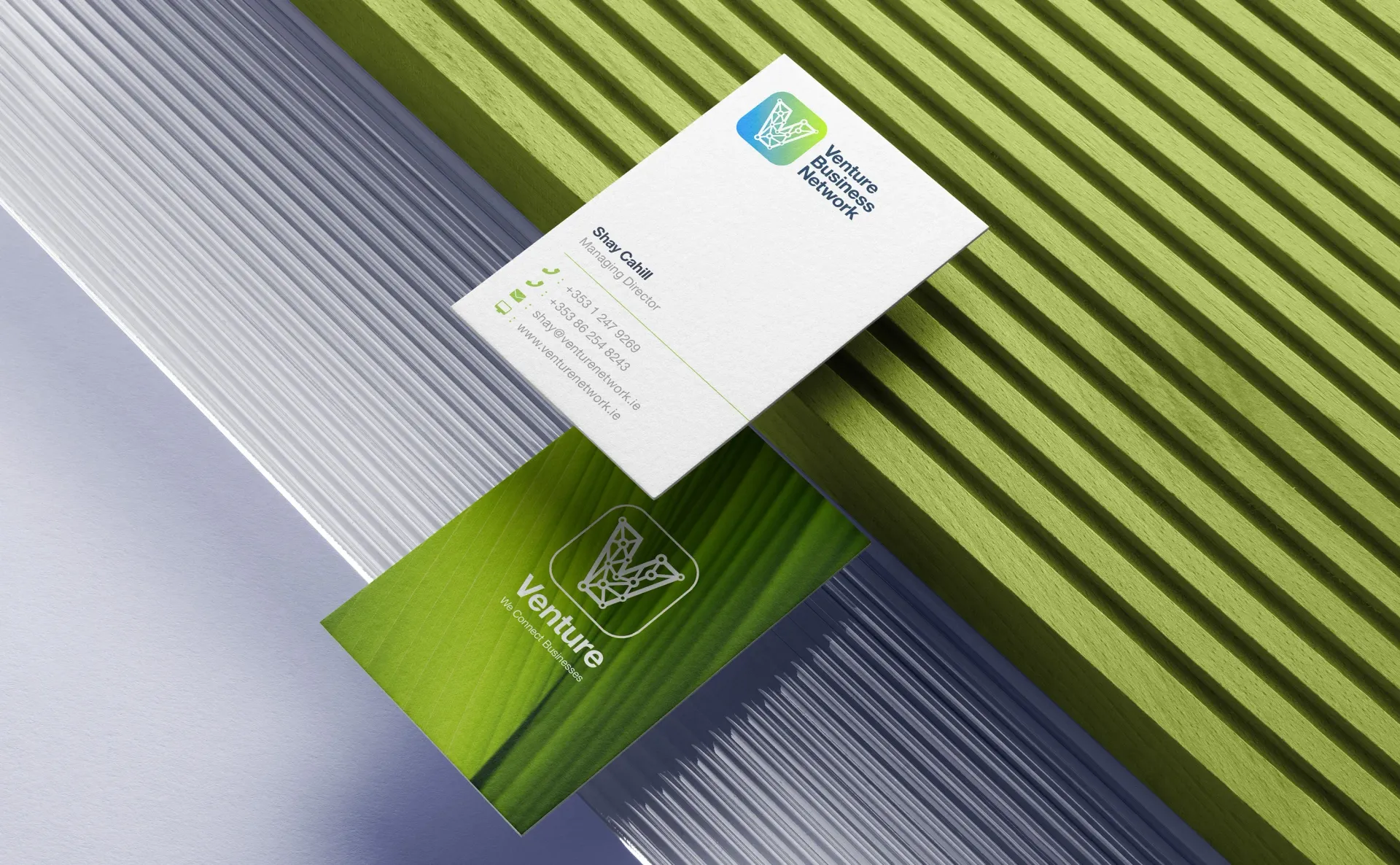 Business cards: green and white cards on green and silver striped backgrounds.