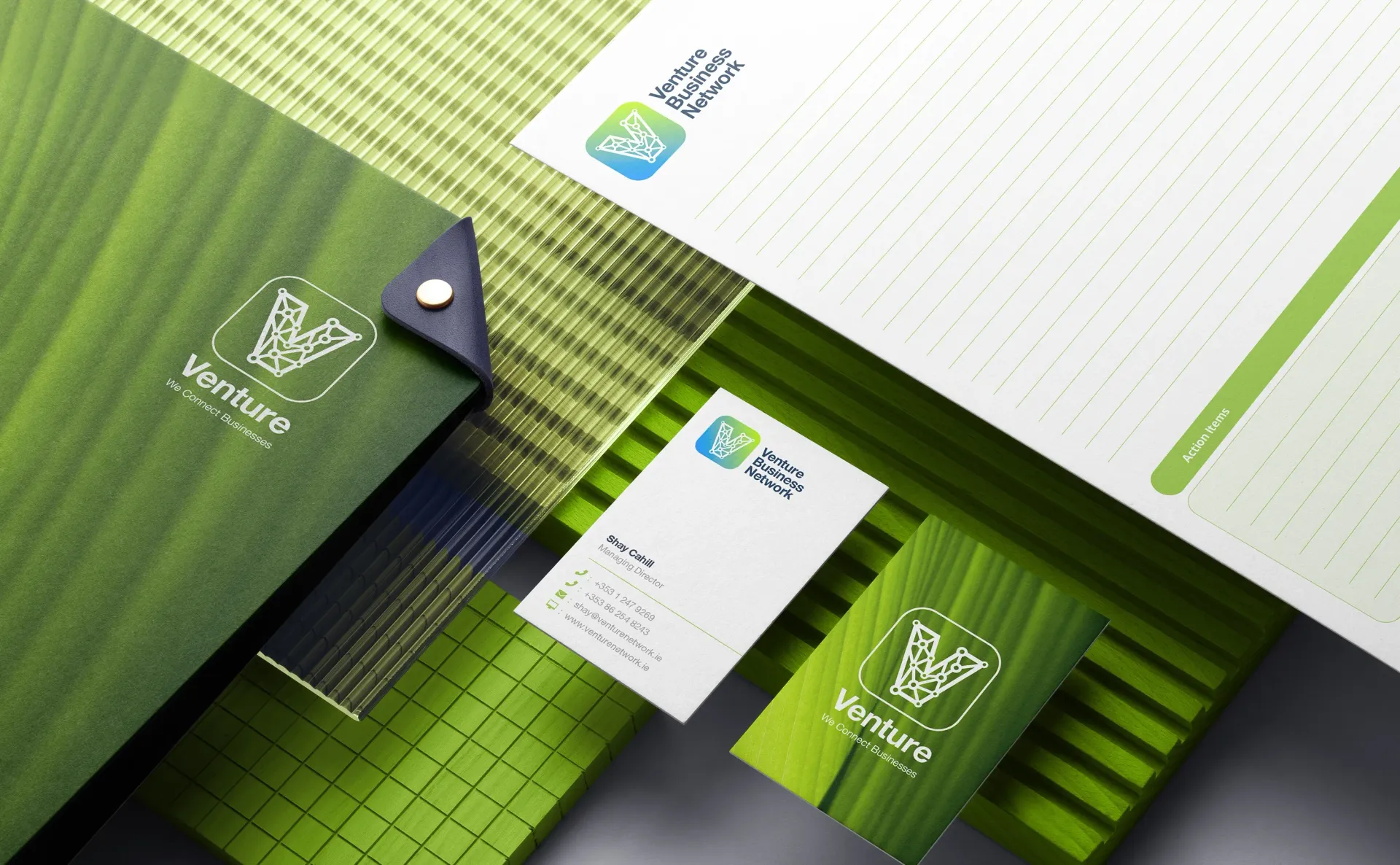 Green and white Venture stationary with logo, including a folder, business card, and letterhead.
