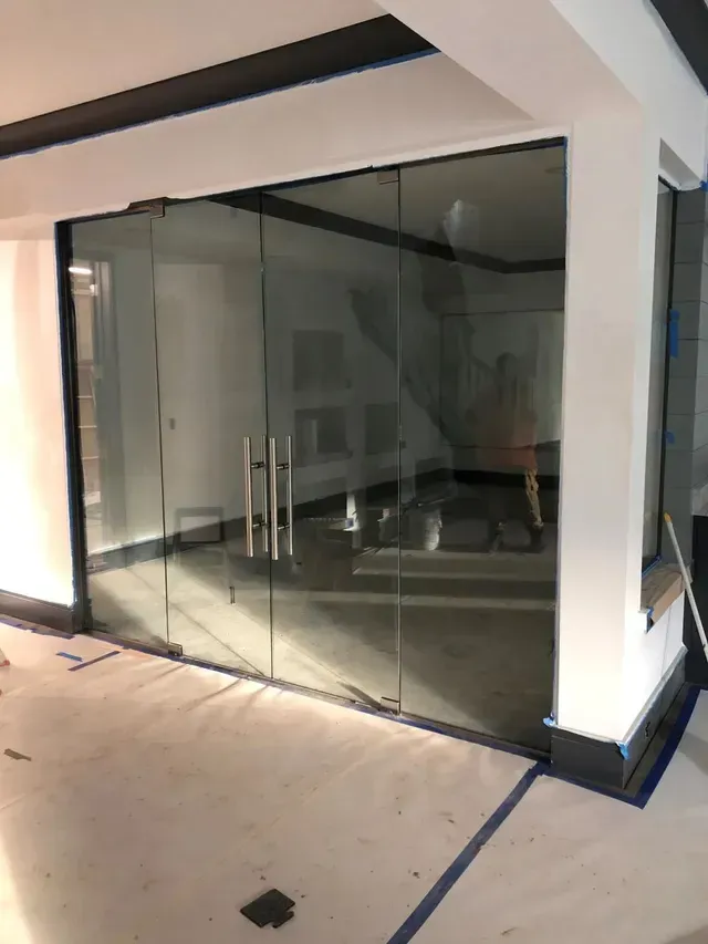 Glass partition with double doors and black frame, blue painter's tape, interior construction.