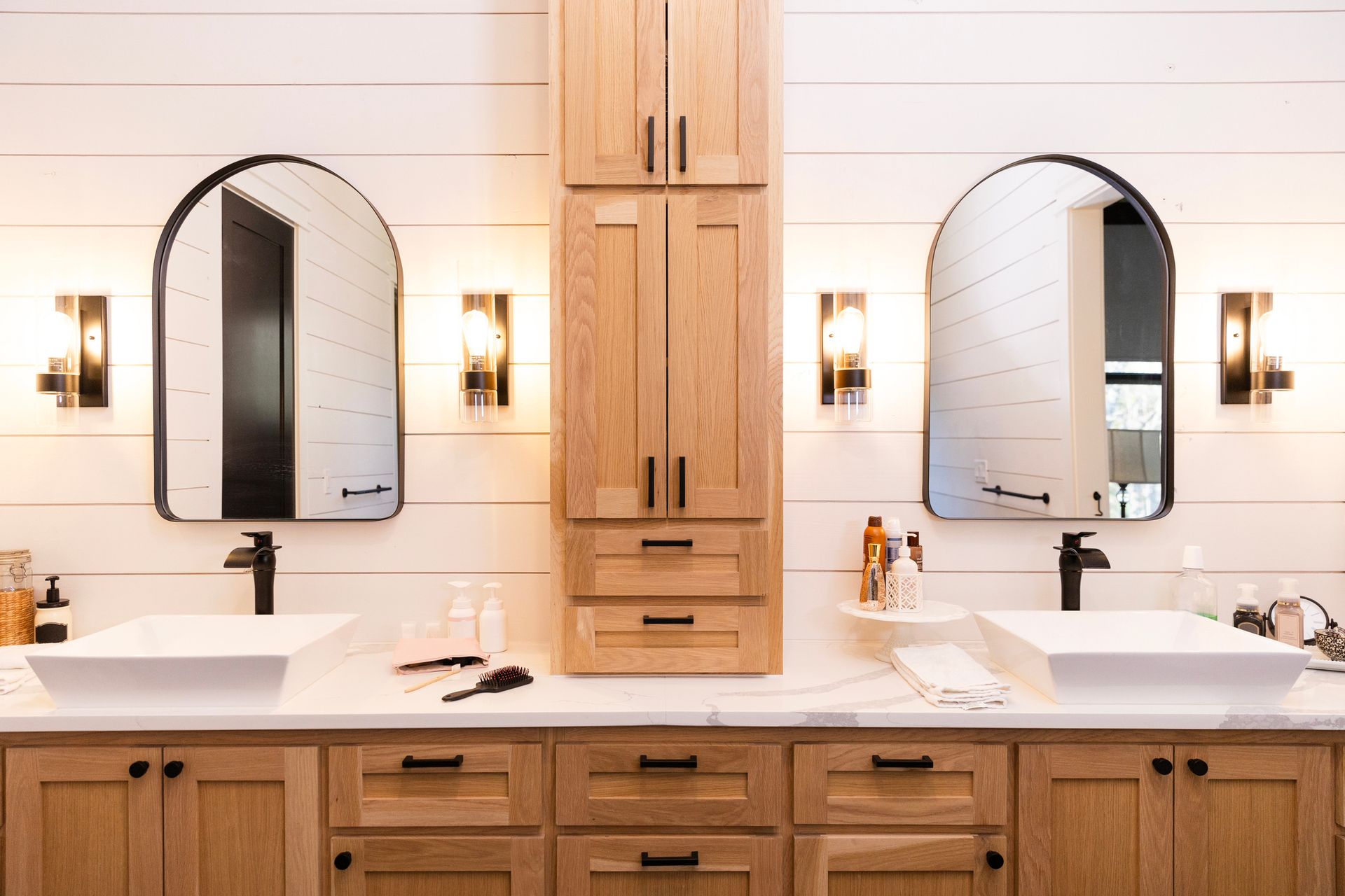 Recently renovated modern bathroom with double sink, natural wood cabinetry, and black hardware.
