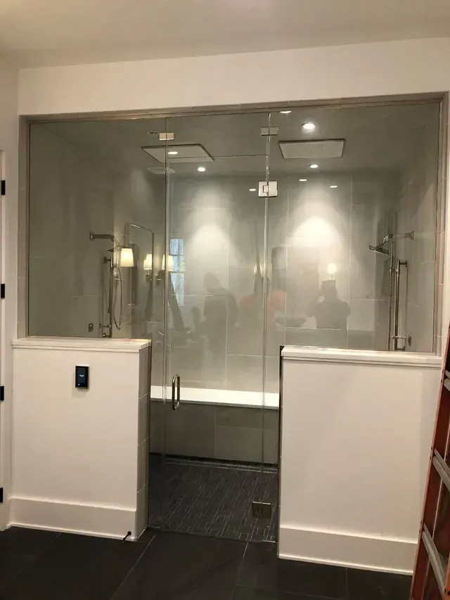 Glass shower enclosure with white trim and marble accents.