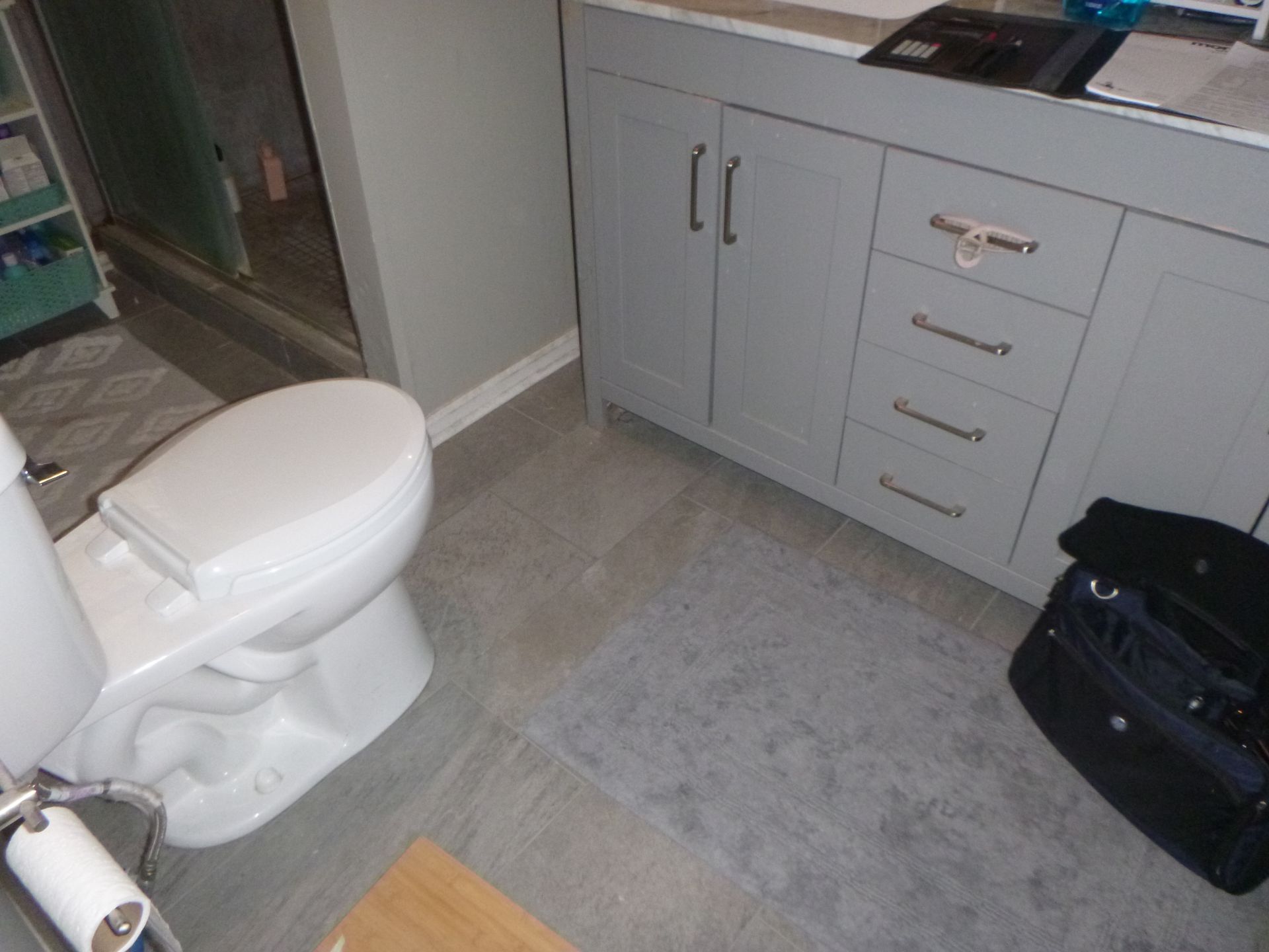 A bathroom with a toilet and a bag on the floor