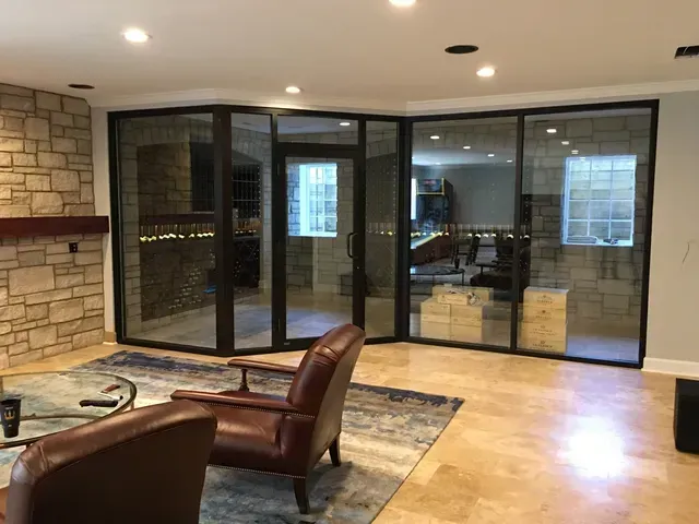 Interior with glass doors and stone accents, two leather chairs on rug, recessed lighting.