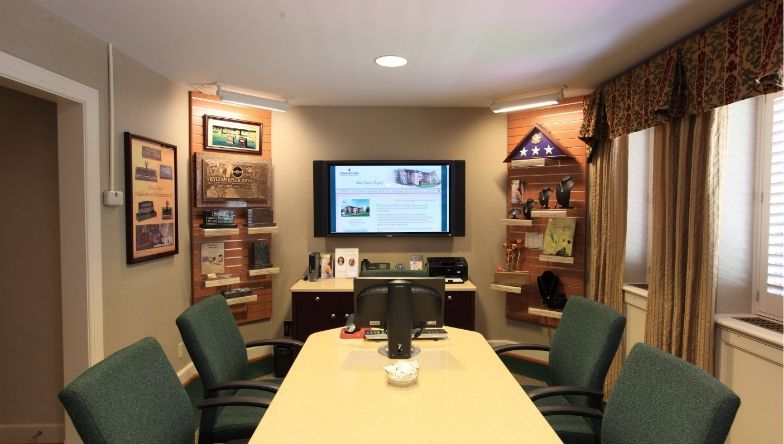 A conference room with a table and chairs and a flat screen tv on the wall.