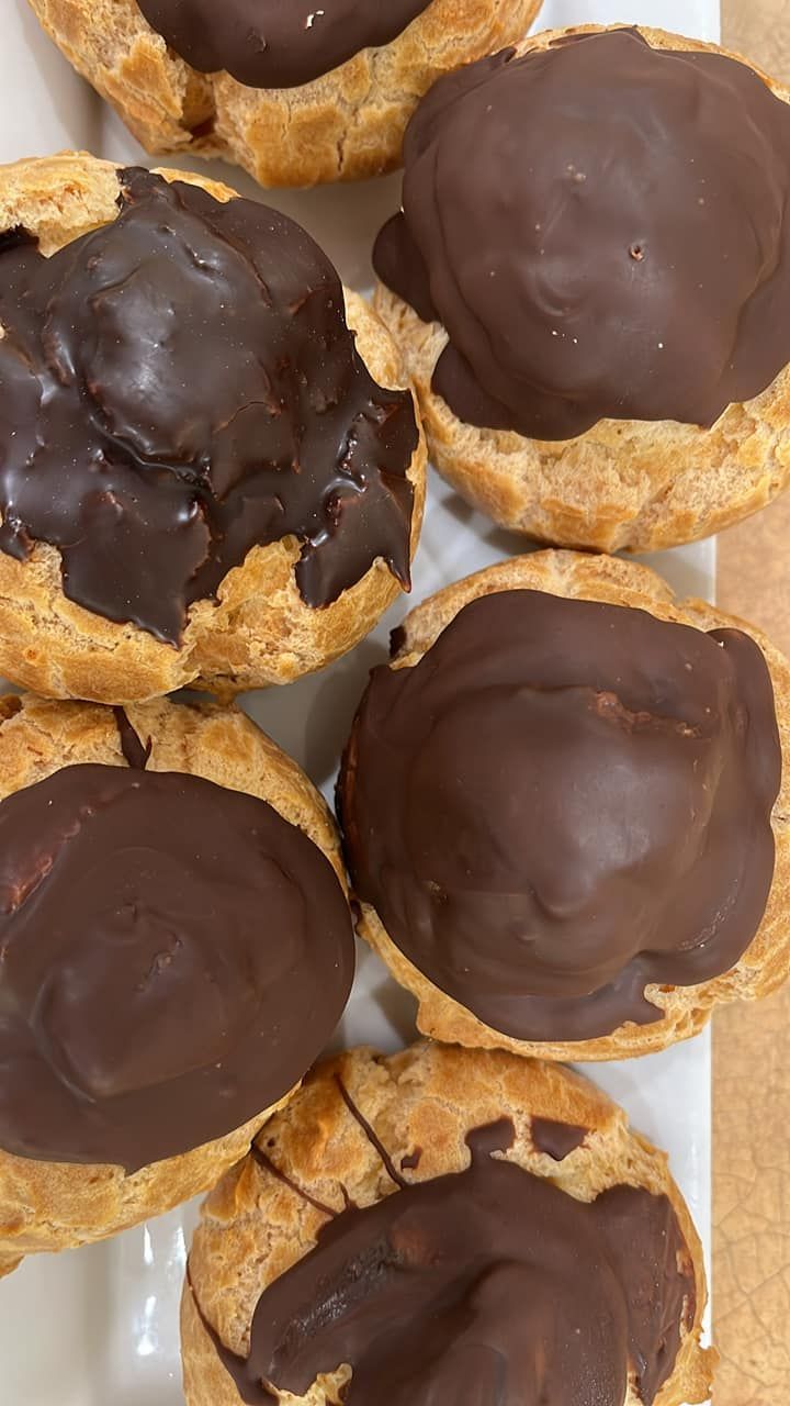 A close up of a white plate topped with chocolate covered pastries.