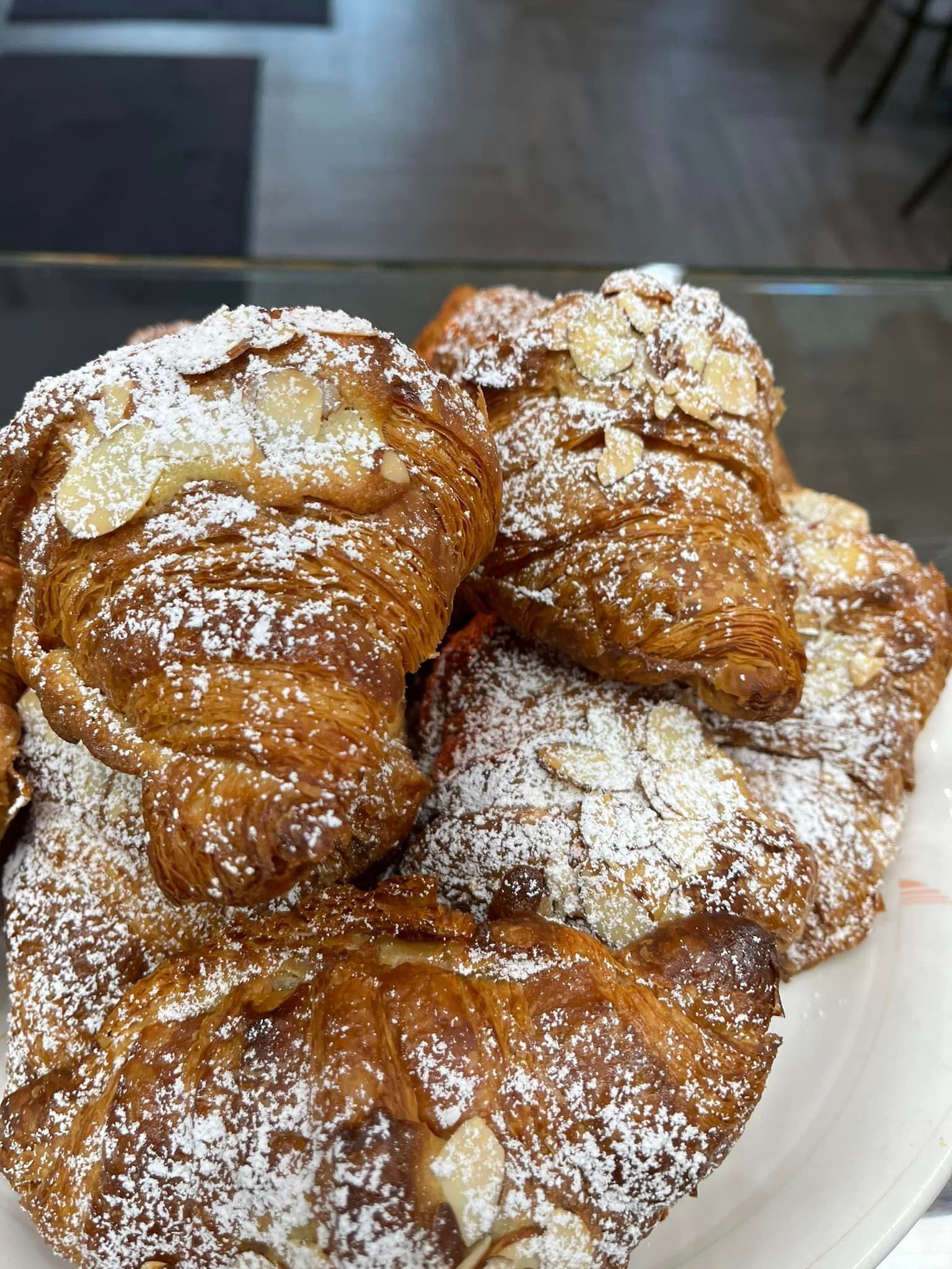 A white plate topped with croissants covered in powdered sugar.