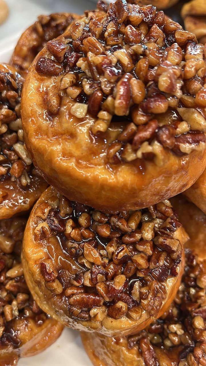 A pile of pecan pie donuts stacked on top of each other on a white plate.