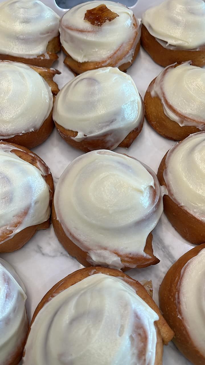 A bunch of cinnamon rolls with white frosting on a tray.