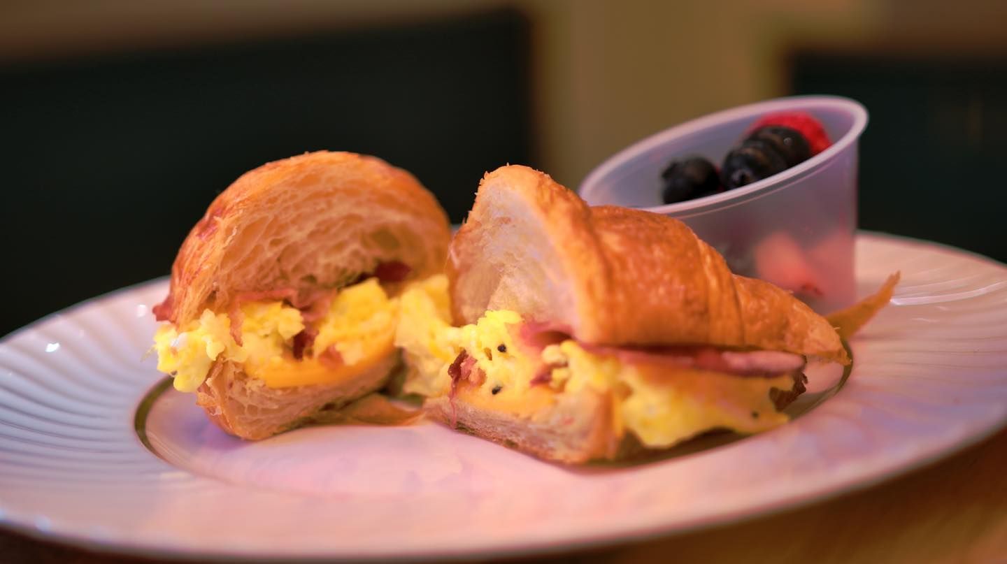 A plate with a sandwich a cookie and grapes on it