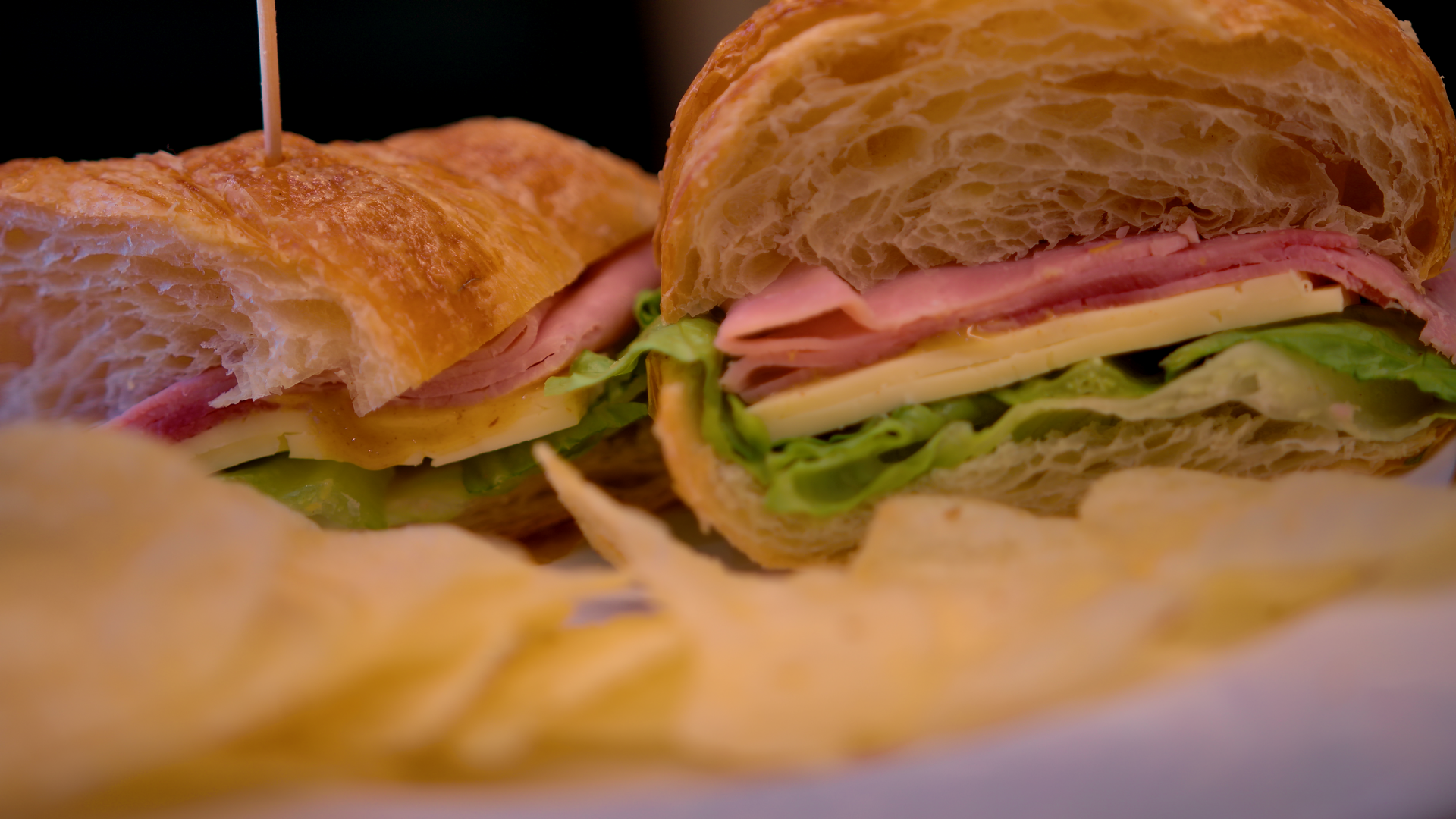 A plate of croissants with powdered sugar on a checkered table cloth.