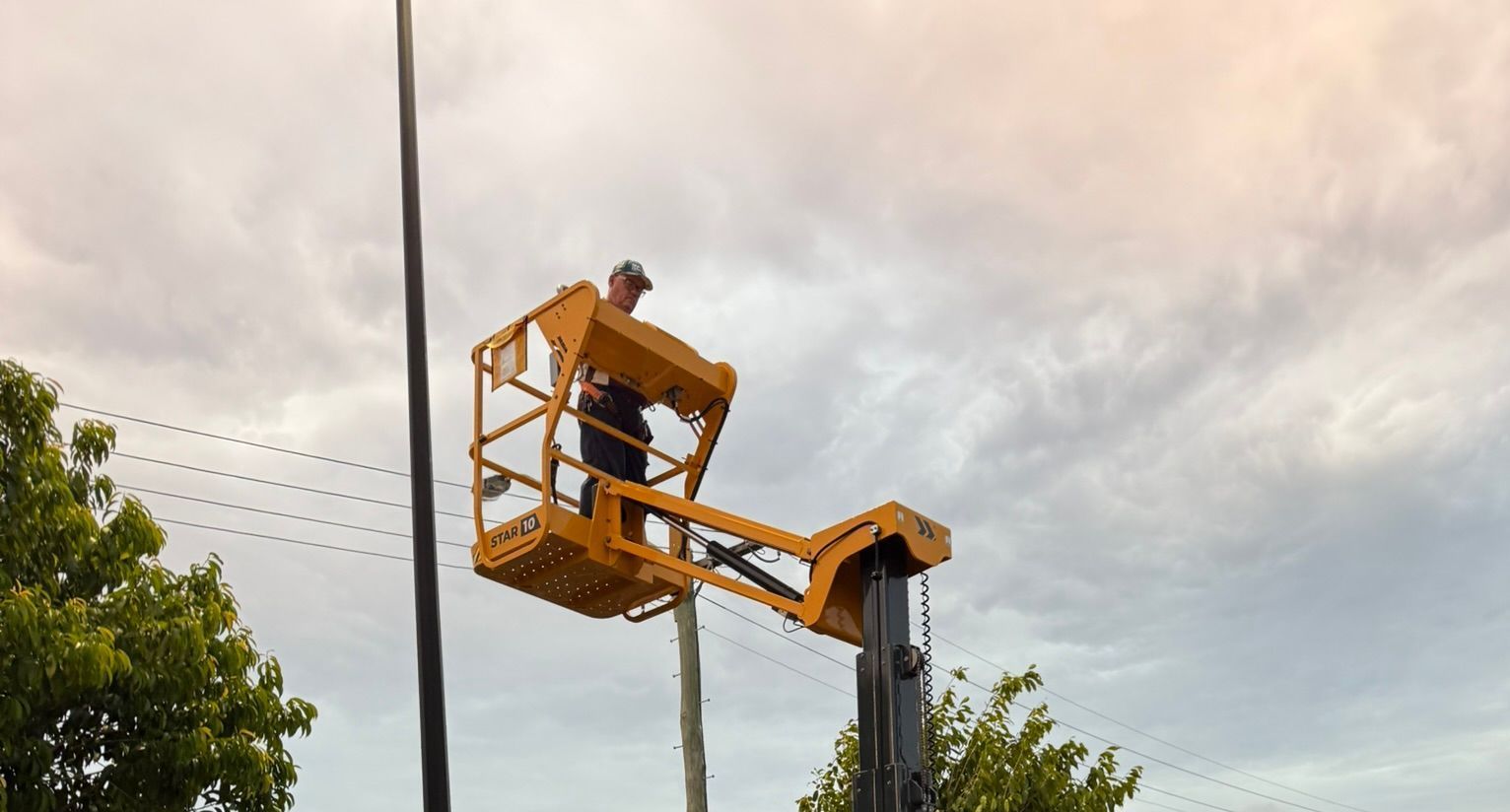 A Man In A Hard Hat Is Sitting In A Lift — B2B Hire In Garbutt, QLD