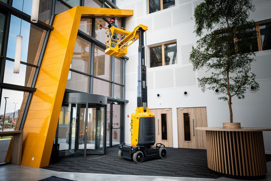 A Man Is Cleaning The Windows Of A Building With A Lift — B2B Hire In Garbutt, QLD