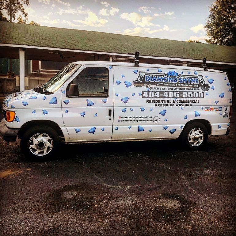 A white van with blue hearts on it is parked in front of a building