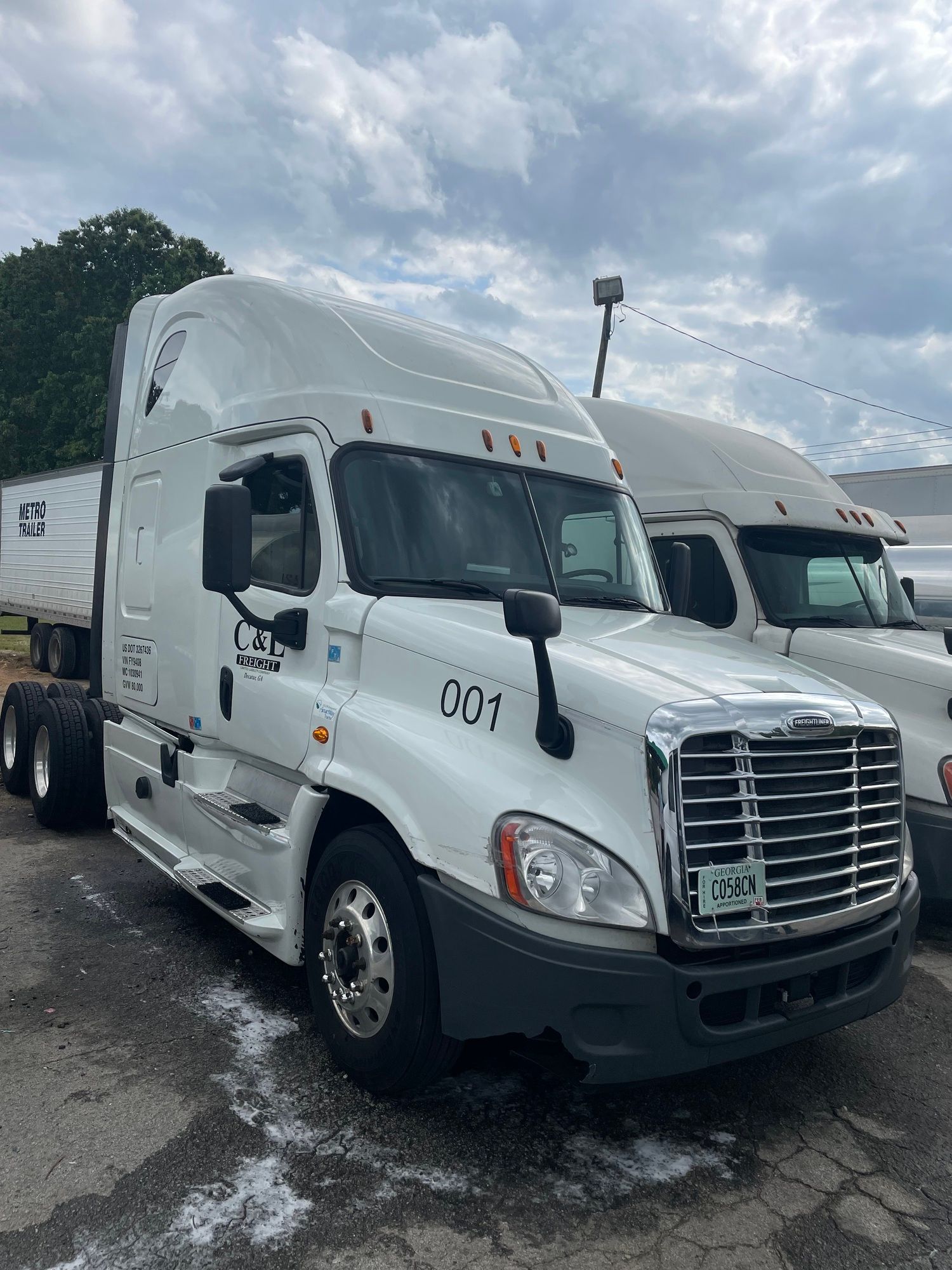 A white semi truck is parked next to another semi truck in a parking lot.