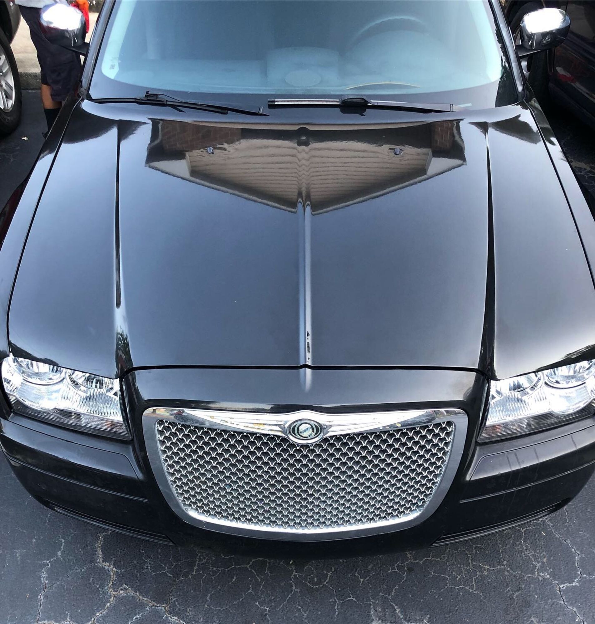 A black chrysler car is parked in a parking lot