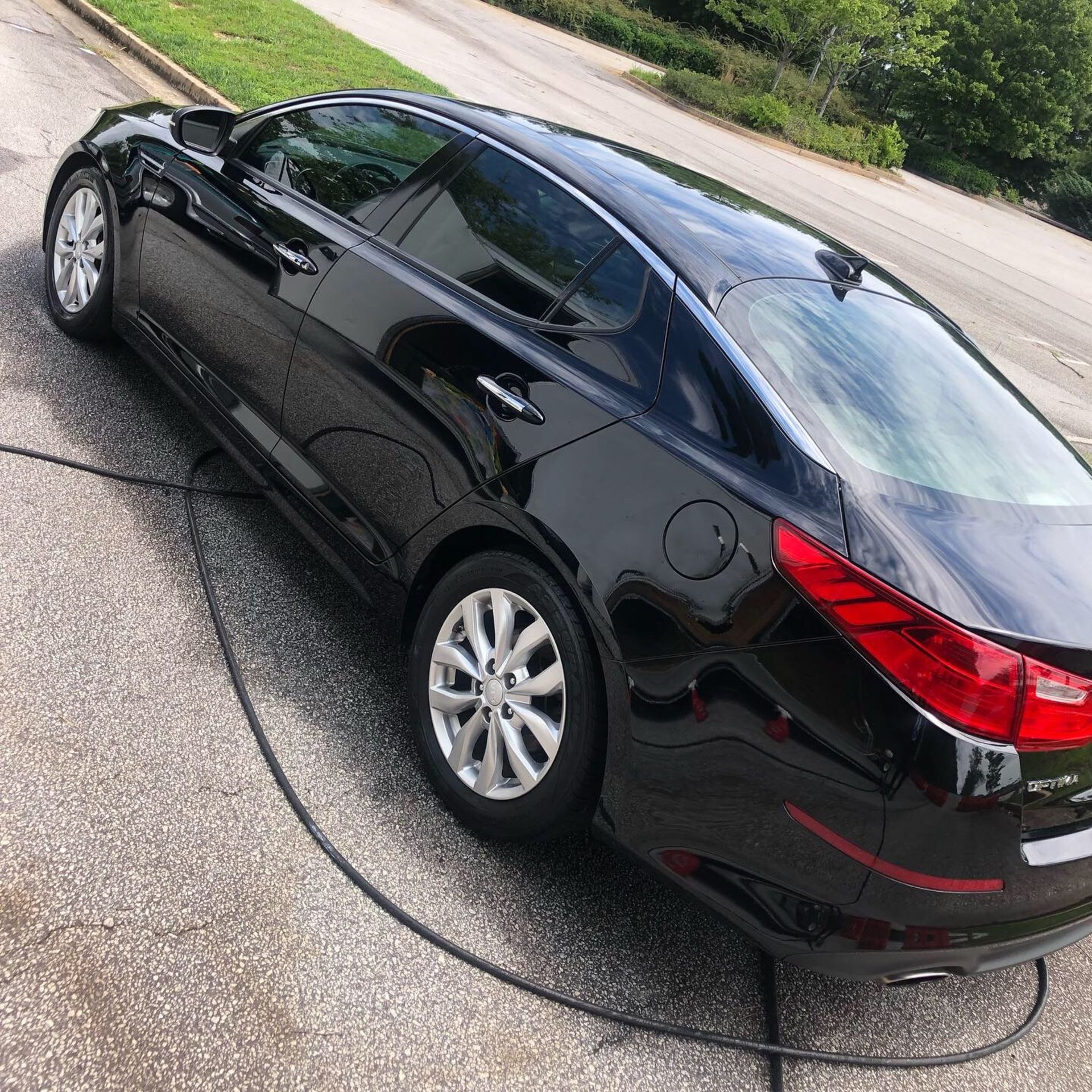 A black car is connected to a hose on the side of the road