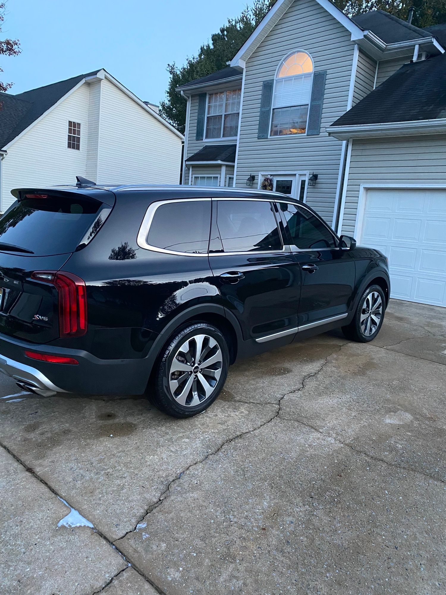 A black suv is parked in a driveway in front of a house.