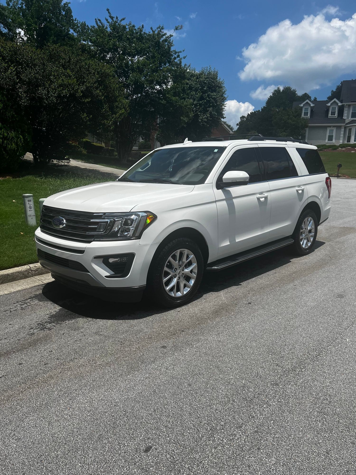 A white suv is parked on the side of the road in front of a house.