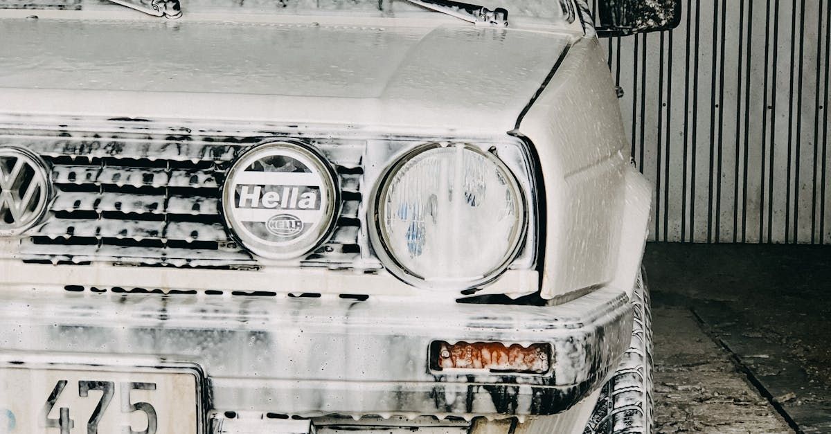 A white car is covered in foam in a garage.
