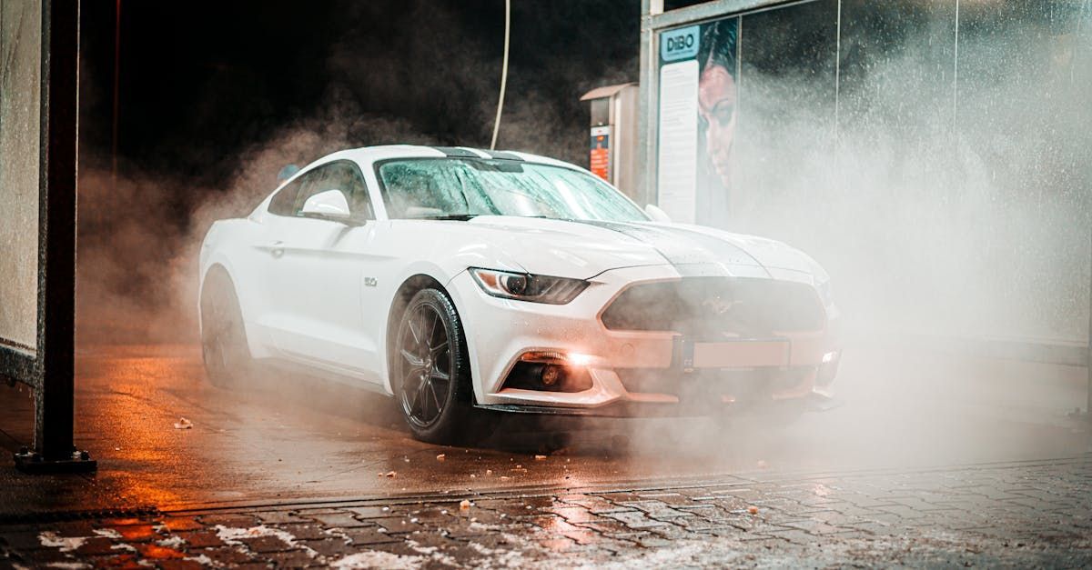 A white ford mustang is being washed in a car wash.