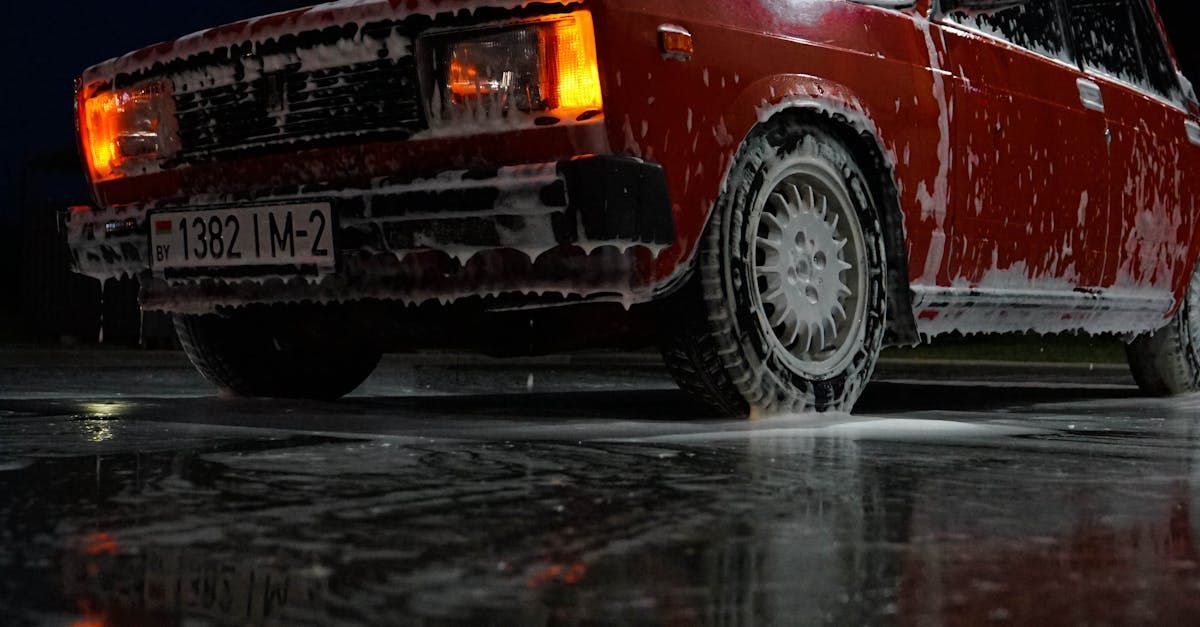 A red car is sitting in a puddle of water.