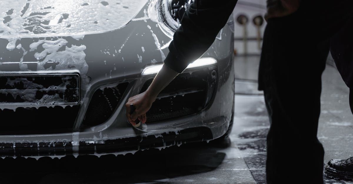 A man is washing a car in a garage.