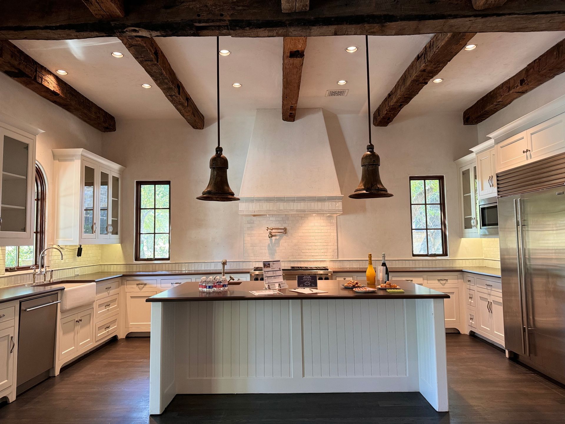 Kitchen with white cabinets, dark island, and exposed wooden beams.