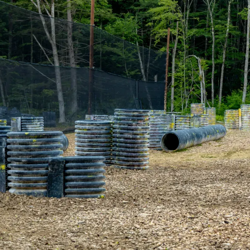 Paintball field with barriers, trees, and netting.