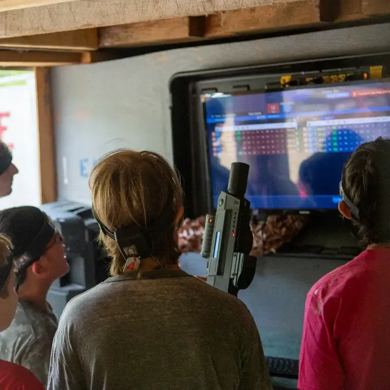 People playing laser tag, looking at a screen displaying game information.