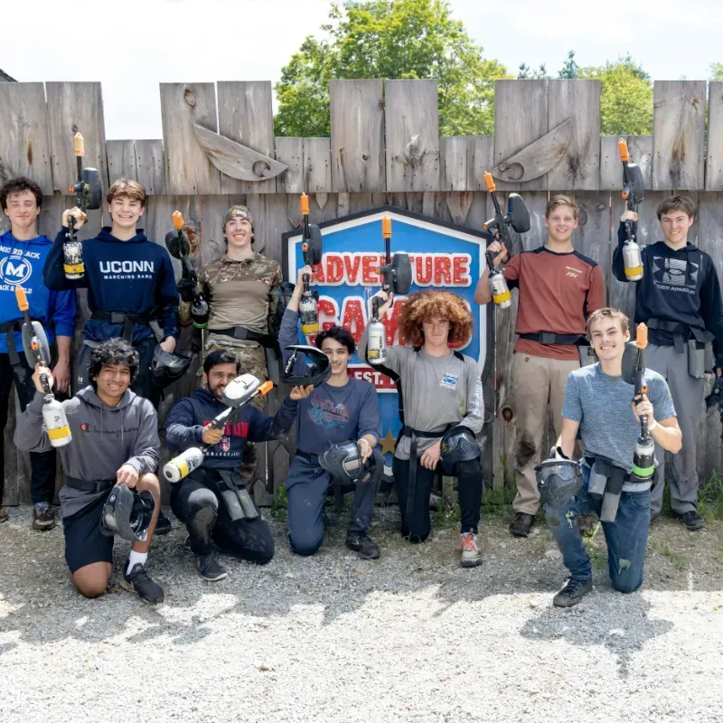 Group of people with paintball guns posing in front of an