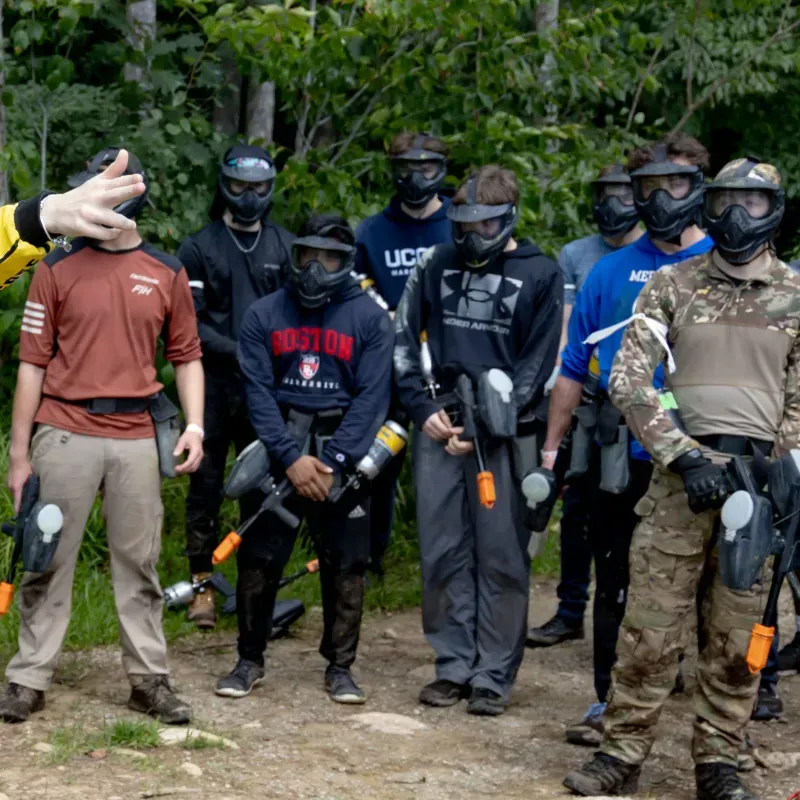 Group of people in paintball gear, ready to play in a wooded area.