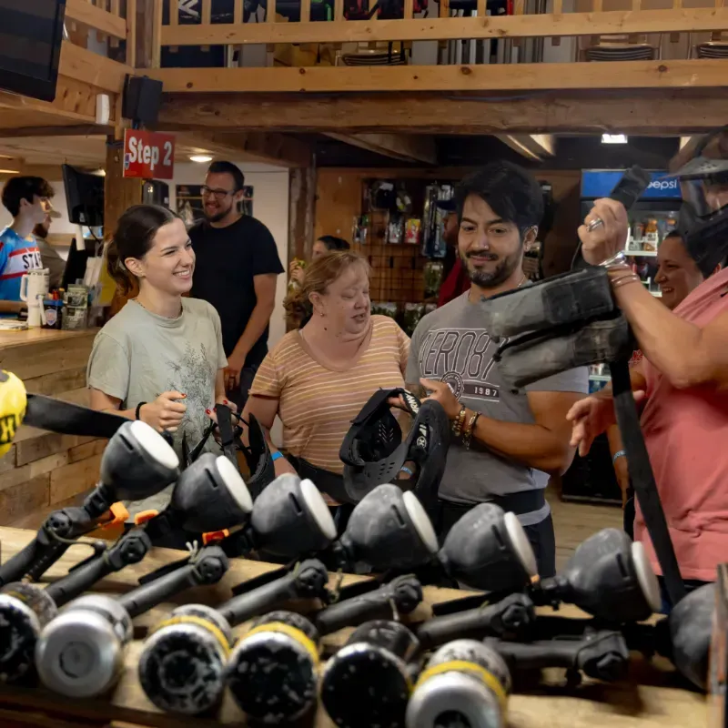 People at a paintball venue preparing for a game. They are smiling and wearing protective gear.