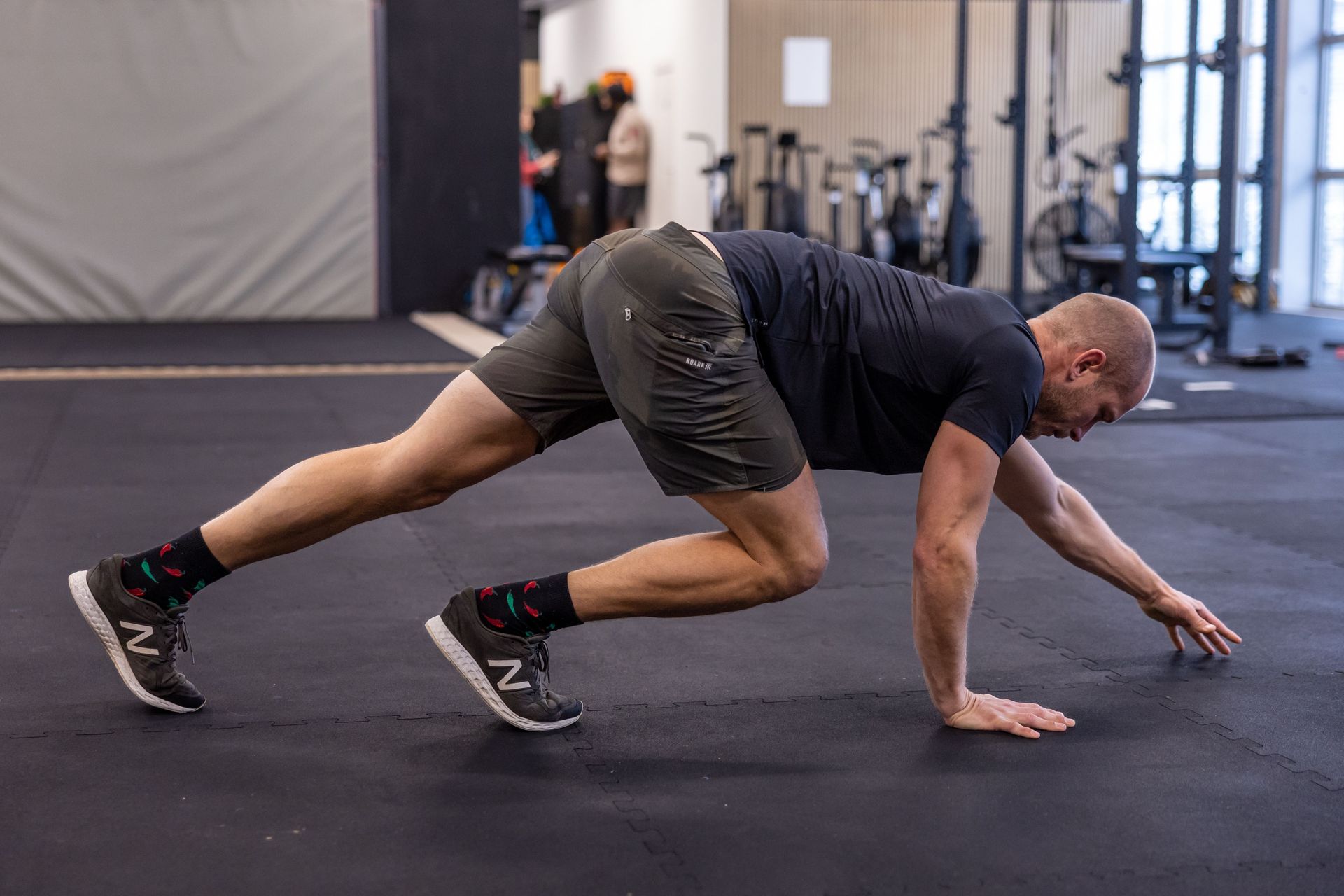 A person in a gym in Thalwil performing a crawling exercise on a black mat, balancing on hands and feet