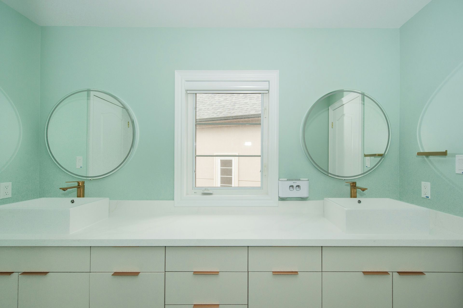 two mirrors, two sinks with a light blue green wall backdrop
