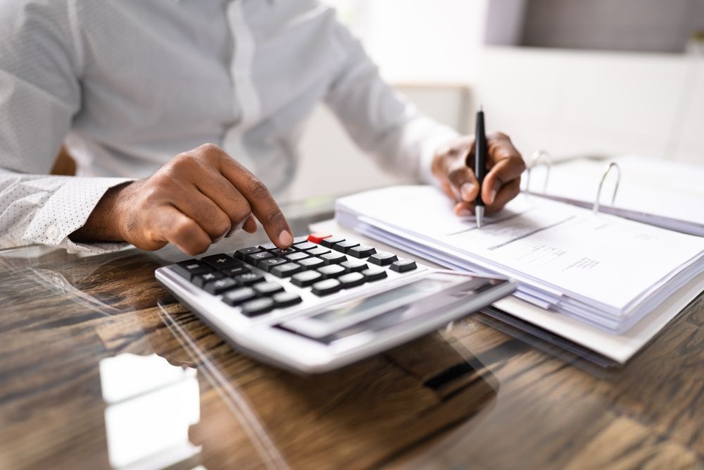 A man is using a calculator and writing on a piece of paper.