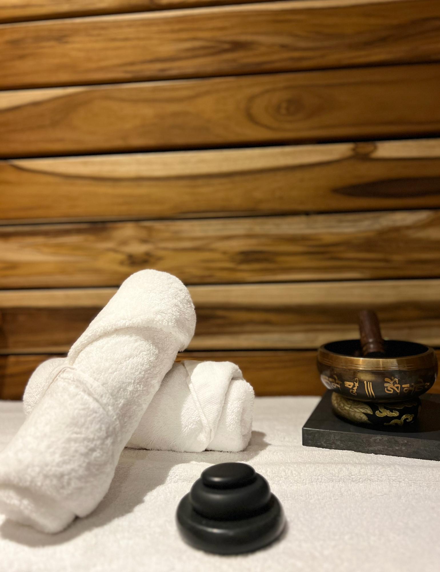 Dos toallas están apiladas una encima de otra sobre una mesa al lado de un cuenco.