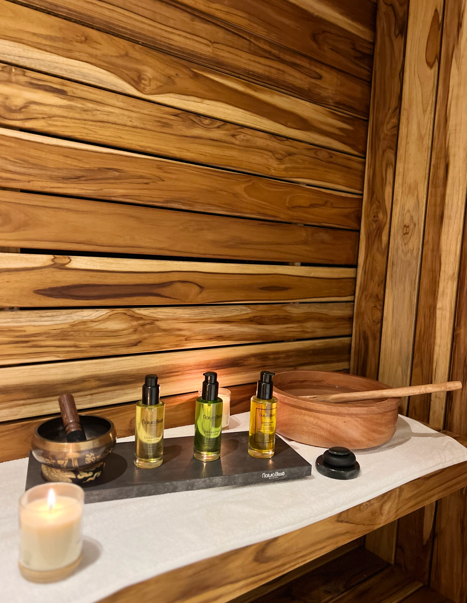 Un estante de madera con botellas de aceite y una vela encima.