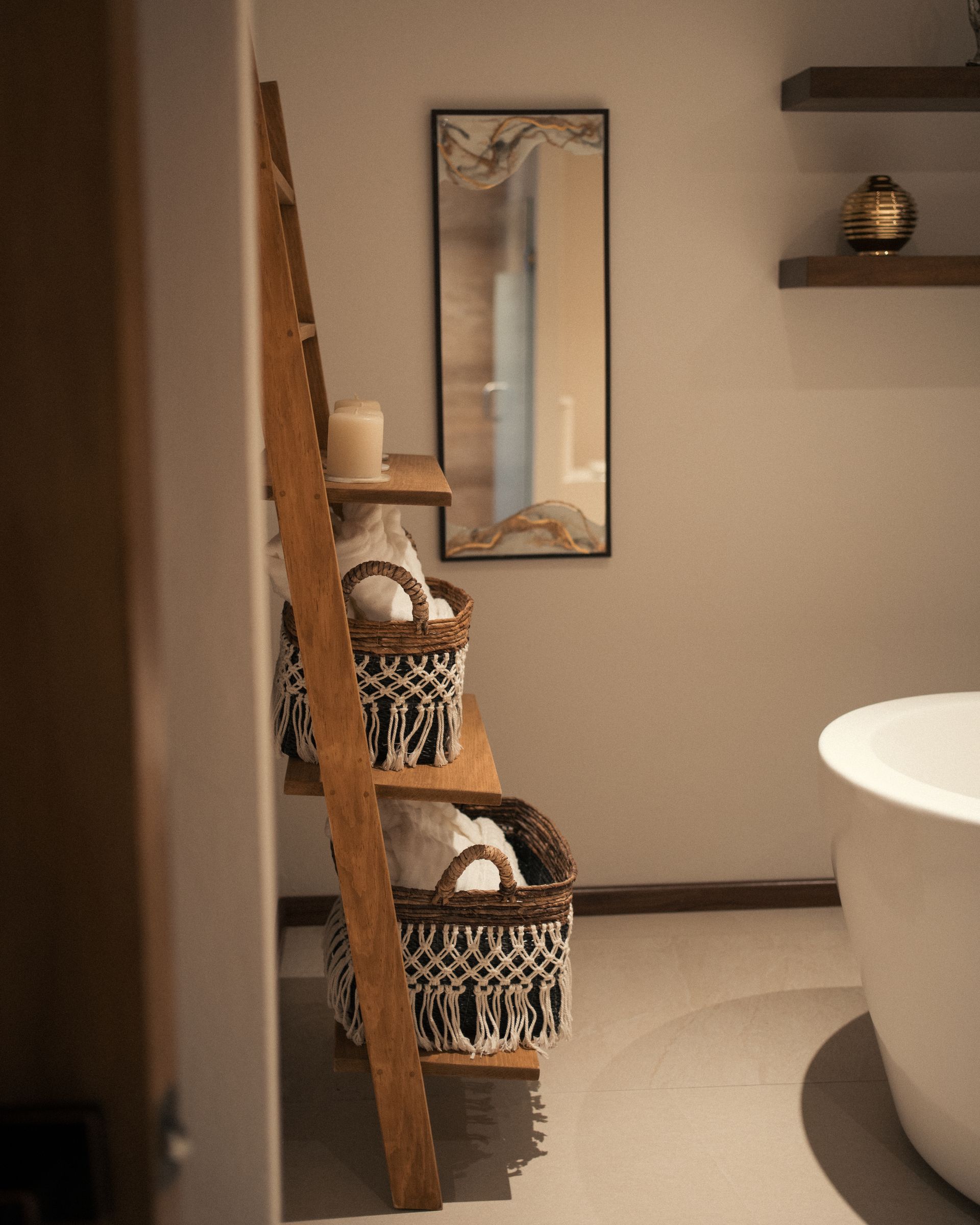 Un baño con bañera y una escalera con cestas encima.