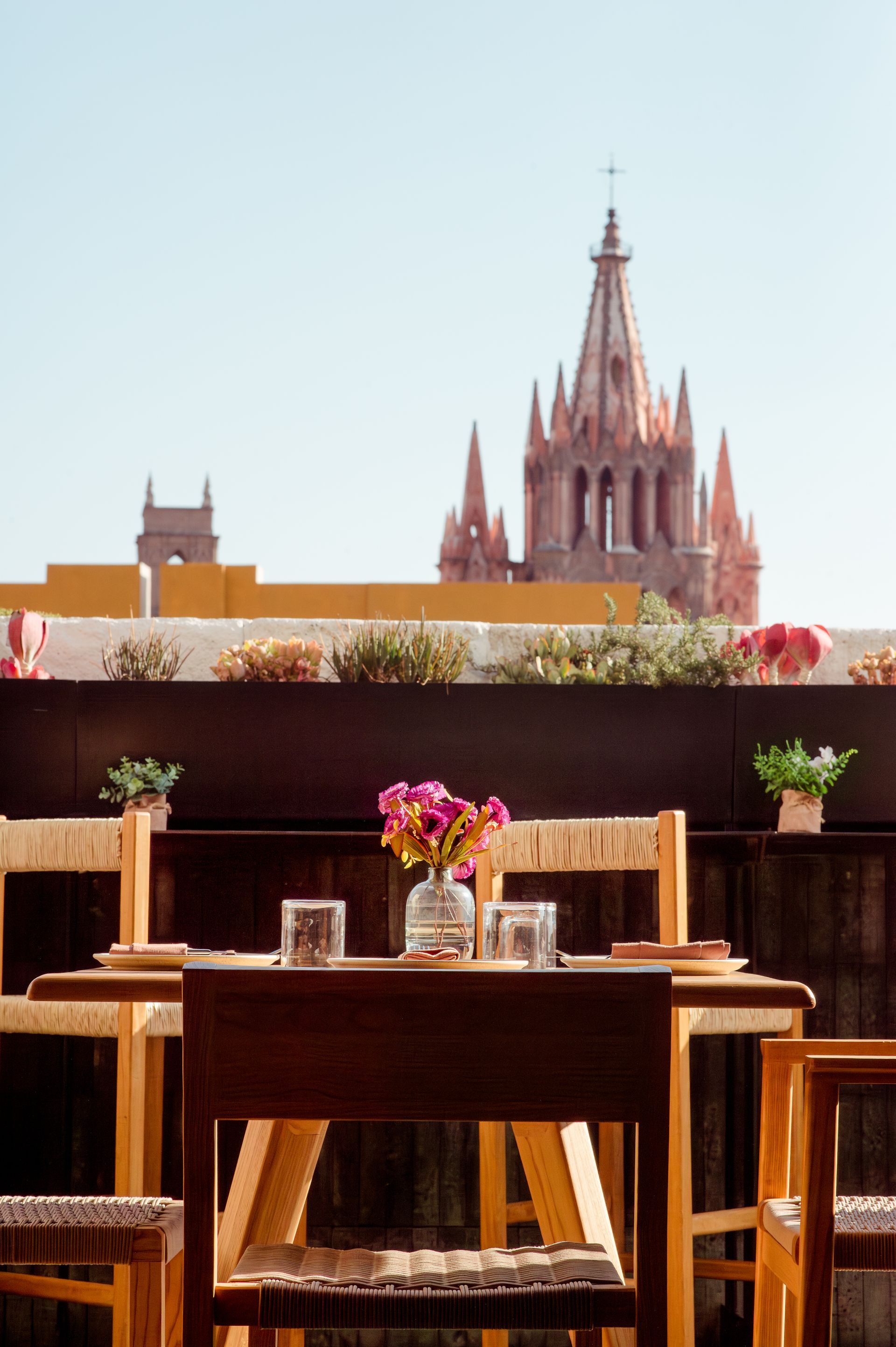 Una mesa con un jarrón de flores encima y una catedral al fondo.