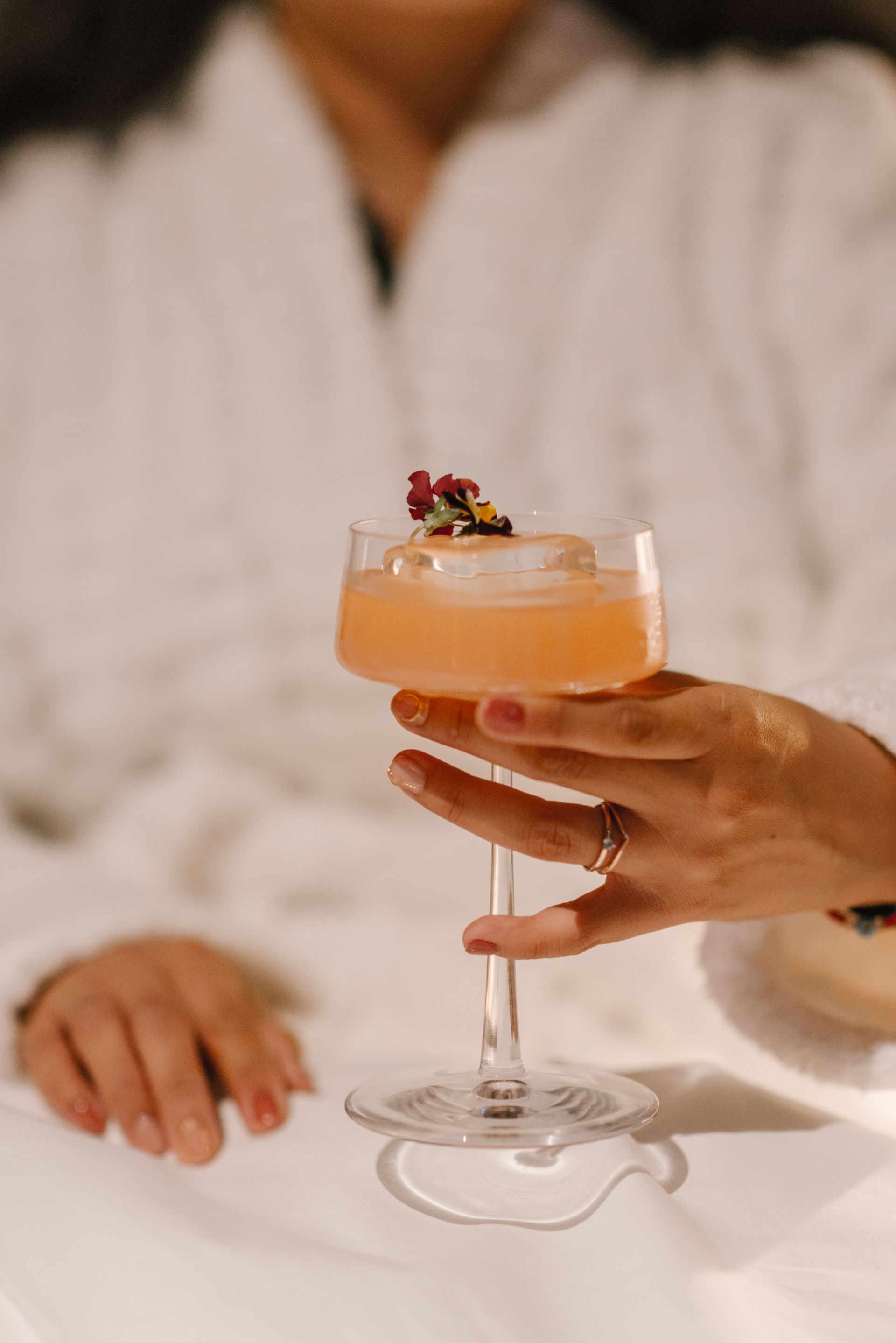 Una mujer en bata de baño sostiene un cóctel en la mano.