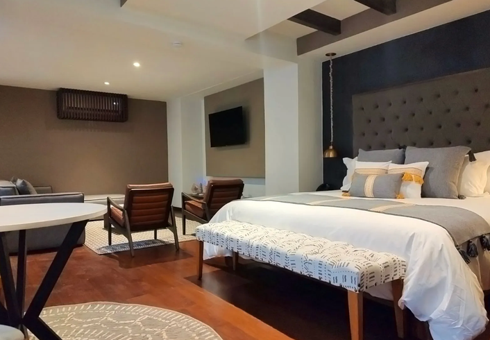 Un dormitorio con una cama king size, sillas, una mesa y un televisor.