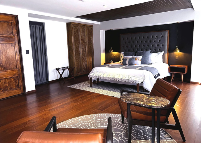 Una habitación de hotel con una cama, sillas, mesa y alfombra.